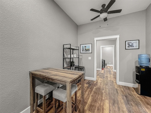 home office featuring ceiling fan, baseboards, wood finished floors, and a textured wall