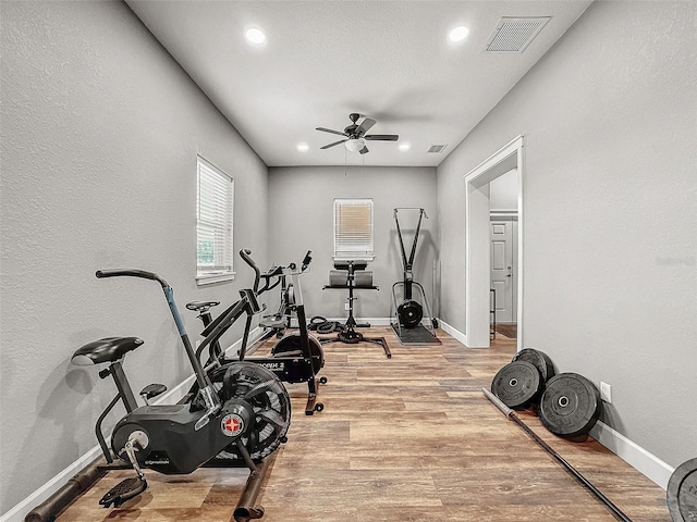 workout area with baseboards, a ceiling fan, visible vents, and light wood-style floors