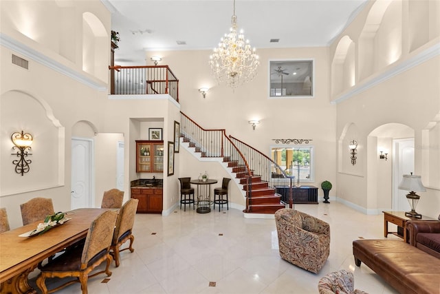 foyer entrance with baseboards, visible vents, arched walkways, stairs, and a notable chandelier