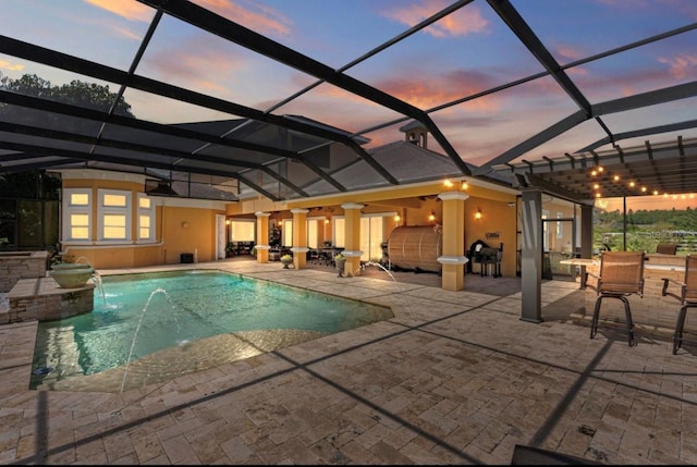 pool at dusk with a patio area, glass enclosure, and an outdoor pool