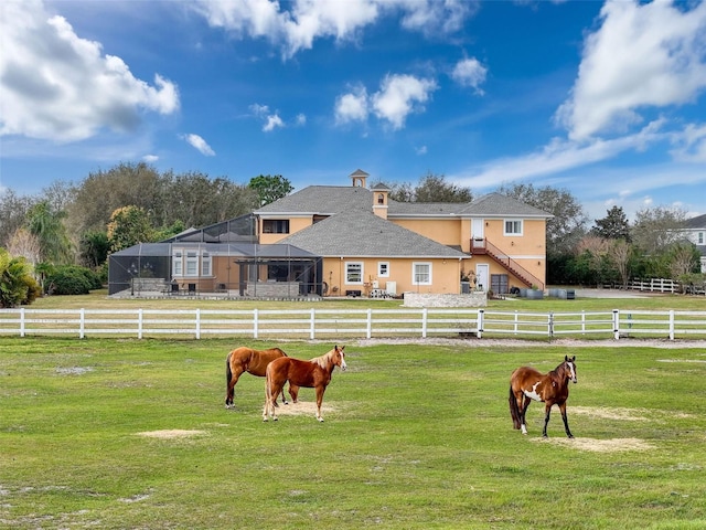 view of community featuring a yard, a rural view, and fence