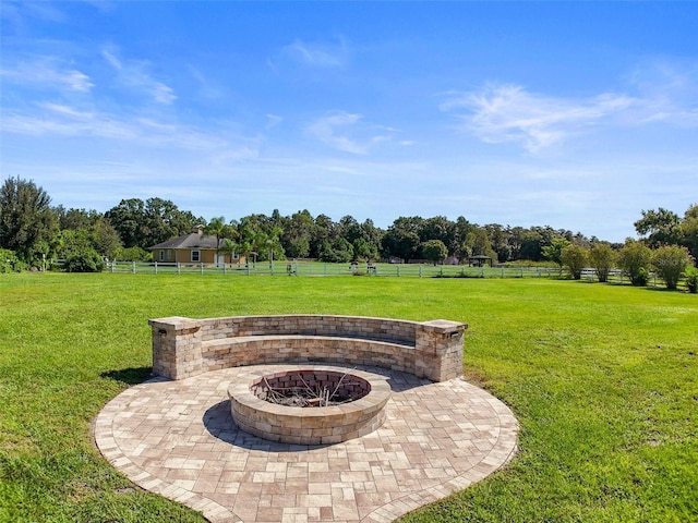 view of yard featuring a patio, an outdoor fire pit, a rural view, and fence