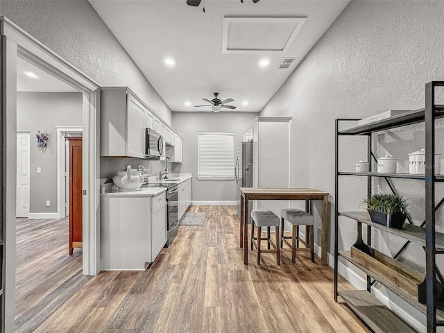 kitchen featuring light wood-style flooring, visible vents, electric stove, light countertops, and stainless steel microwave