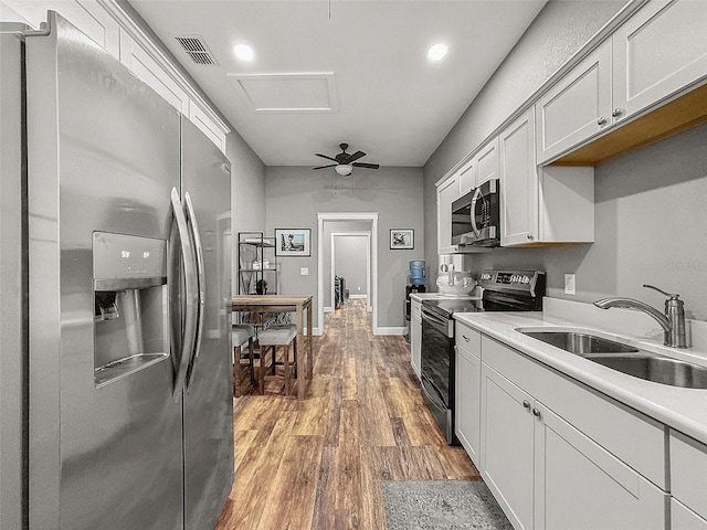 kitchen with light wood finished floors, visible vents, appliances with stainless steel finishes, light countertops, and a sink