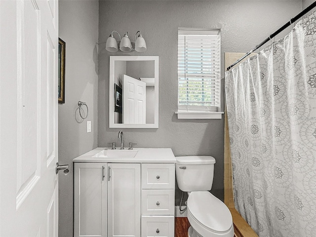 full bathroom featuring toilet, a textured wall, a shower with shower curtain, and vanity