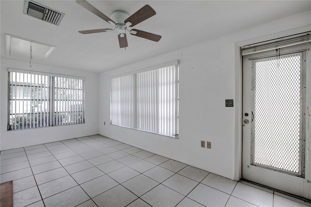 tiled empty room featuring ceiling fan and a wealth of natural light