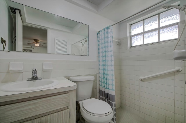 bathroom featuring vanity, tile walls, toilet, a shower with curtain, and ceiling fan