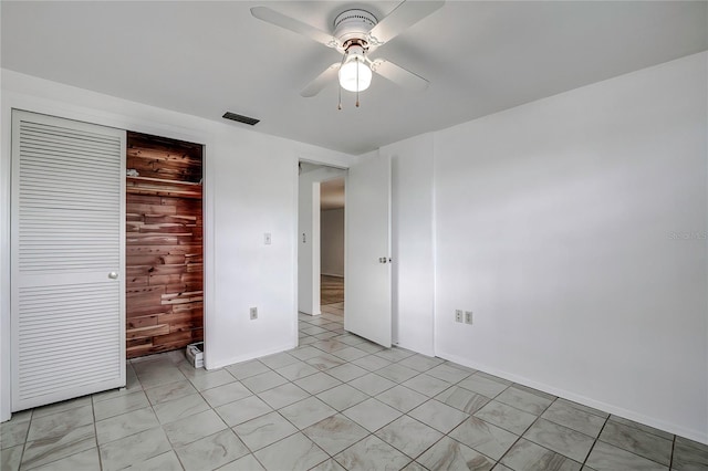 unfurnished bedroom featuring a closet, ceiling fan, and wooden walls