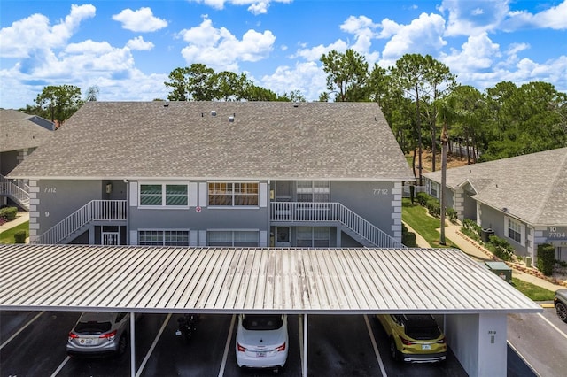 rear view of property with roof with shingles, stairway, a standing seam roof, and covered and uncovered parking