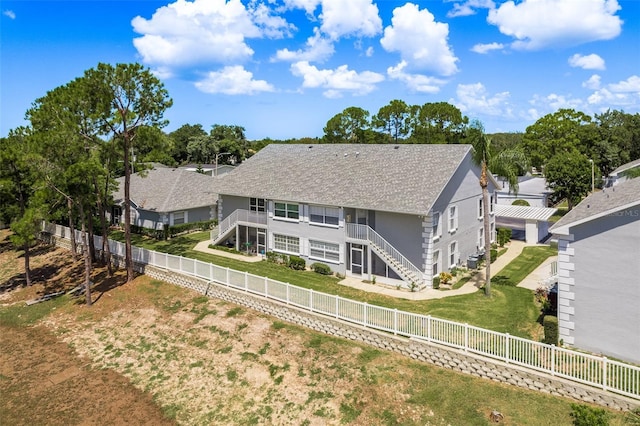 back of property with a fenced backyard, stairs, a residential view, and stucco siding