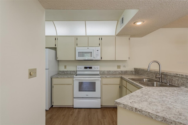 kitchen featuring white appliances, a sink, visible vents, light countertops, and cream cabinetry