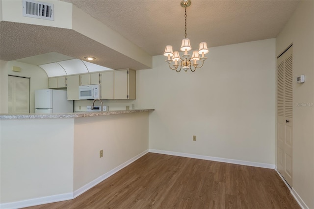 kitchen featuring white appliances, baseboards, visible vents, wood finished floors, and pendant lighting