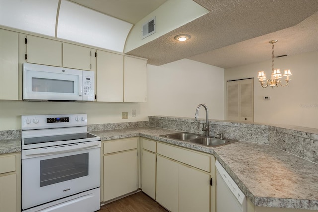 kitchen featuring cream cabinets, a peninsula, white appliances, a sink, and light countertops