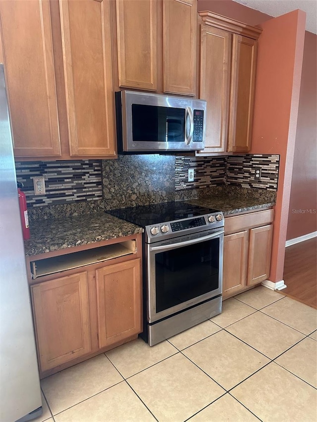 kitchen with light tile patterned flooring, stainless steel appliances, and decorative backsplash