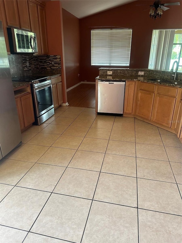 kitchen with lofted ceiling, light tile patterned floors, sink, and stainless steel appliances