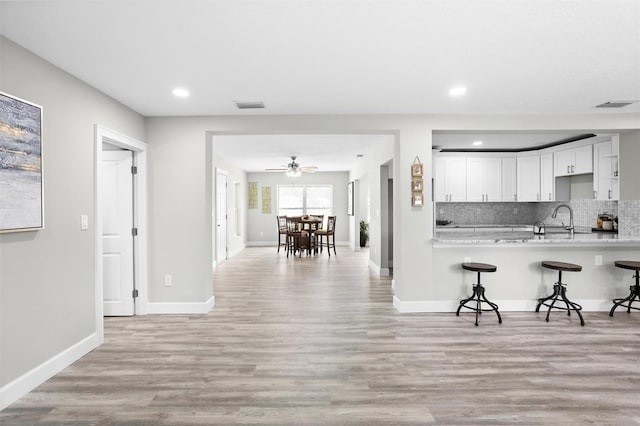 kitchen with light wood-type flooring, white cabinetry, kitchen peninsula, and a breakfast bar area