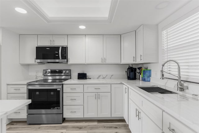 kitchen featuring stainless steel appliances, sink, light wood-type flooring, and white cabinetry