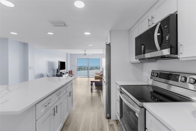 kitchen featuring white cabinetry, light stone counters, stainless steel appliances, and light hardwood / wood-style floors