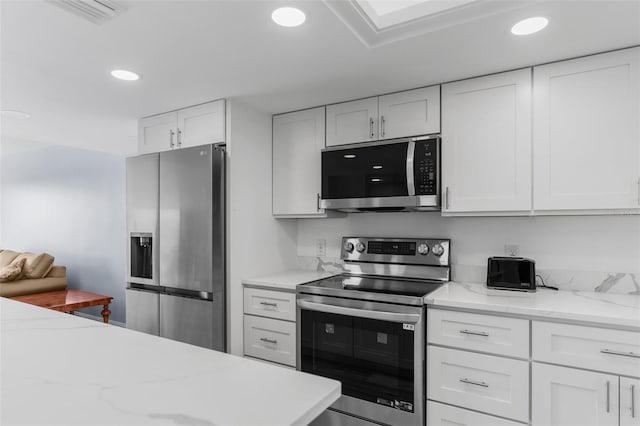 kitchen featuring light stone counters, appliances with stainless steel finishes, and white cabinets