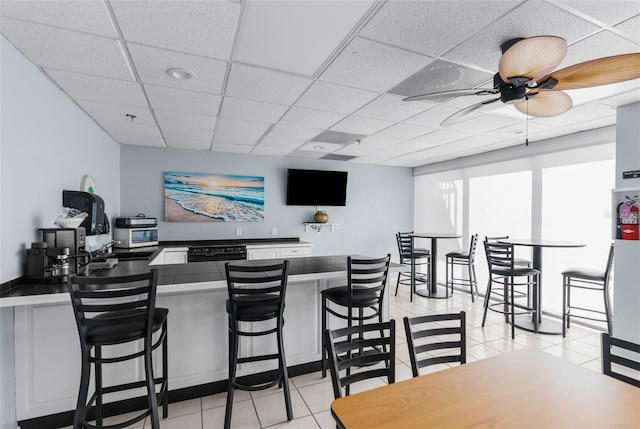 tiled dining room featuring ceiling fan and a drop ceiling