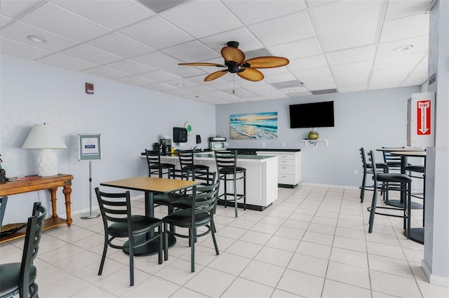 dining space featuring ceiling fan, light tile patterned floors, and a drop ceiling