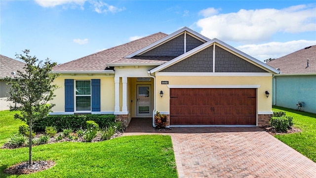 view of front of home featuring roof with shingles, an attached garage, decorative driveway, a front lawn, and stucco siding