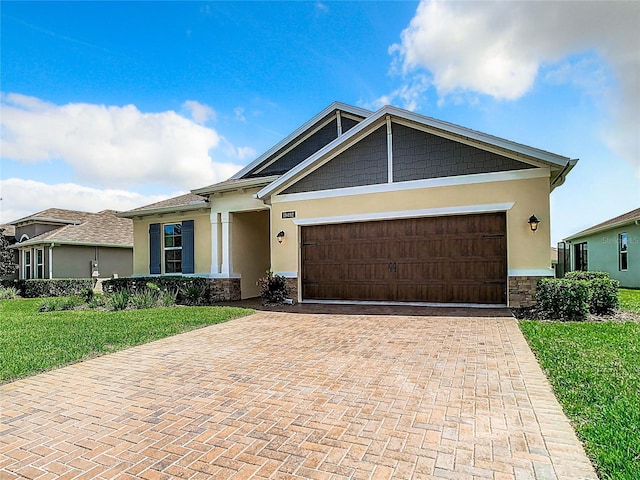 view of front of home with an attached garage, stone siding, decorative driveway, and stucco siding