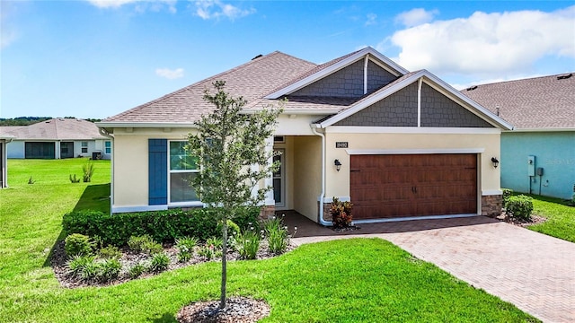 view of front of house featuring decorative driveway, stucco siding, a shingled roof, an attached garage, and a front yard