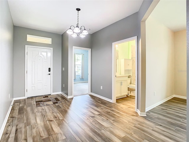 entryway featuring a notable chandelier, baseboards, and wood finished floors