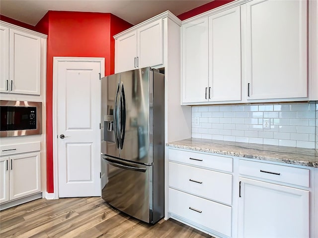 kitchen with tasteful backsplash, stainless steel appliances, light wood finished floors, and white cabinets