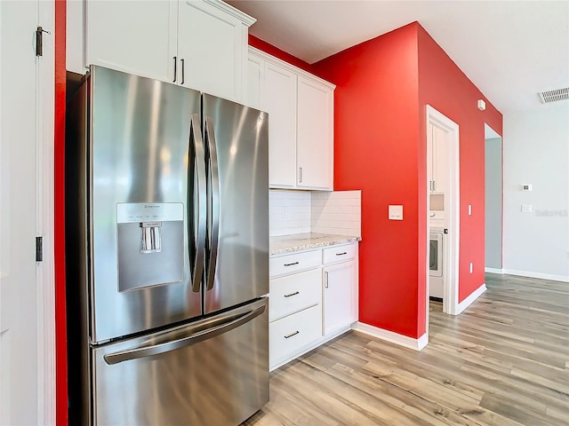 kitchen featuring white cabinets, stainless steel fridge, backsplash, and light hardwood / wood-style flooring