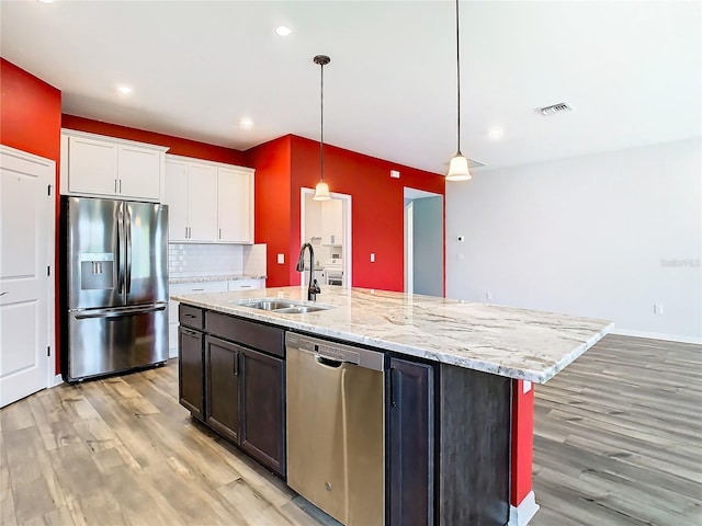 kitchen with a center island with sink, stainless steel appliances, white cabinets, a sink, and light wood-type flooring