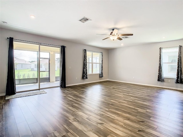 empty room featuring dark wood-style floors, baseboards, visible vents, and a ceiling fan
