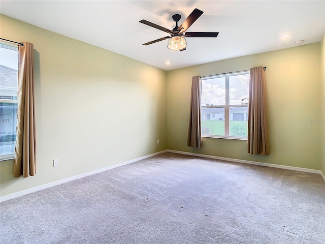 carpeted spare room with ceiling fan and baseboards
