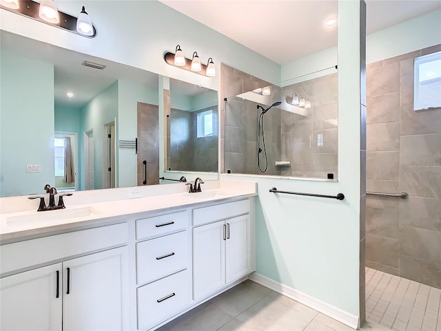 bathroom with tiled shower, tile patterned flooring, and vanity