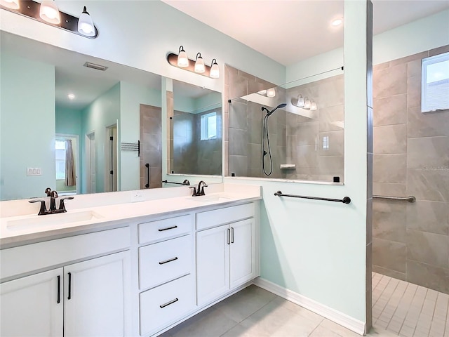 full bathroom with double vanity, walk in shower, a sink, and visible vents