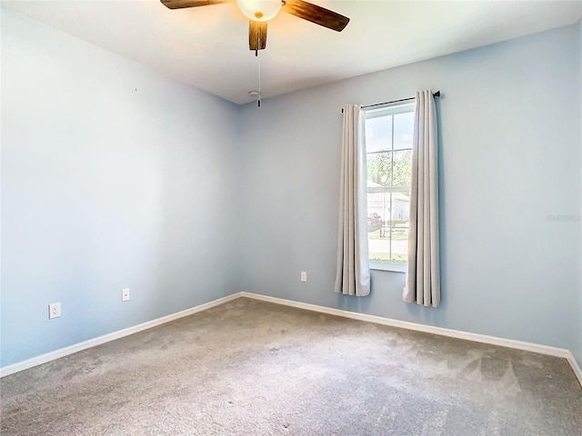 carpeted spare room featuring a ceiling fan and baseboards