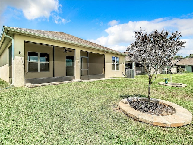 rear view of property featuring ceiling fan, central AC, a lawn, and stucco siding