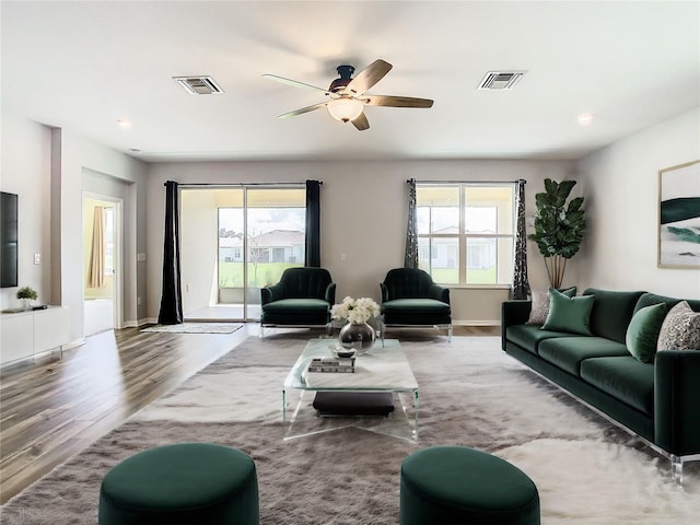 living room with a ceiling fan, baseboards, visible vents, and wood finished floors