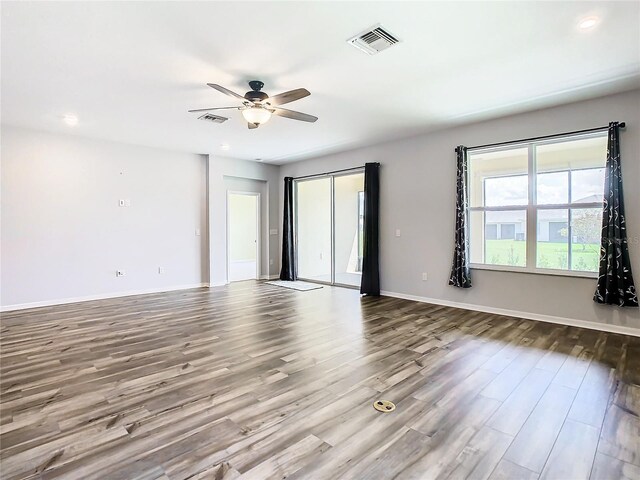 unfurnished room with ceiling fan, wood finished floors, visible vents, and baseboards