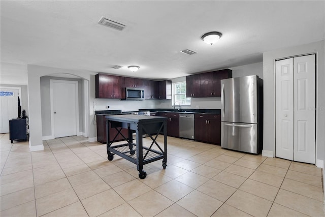 kitchen with light tile patterned flooring, dark brown cabinetry, sink, and appliances with stainless steel finishes