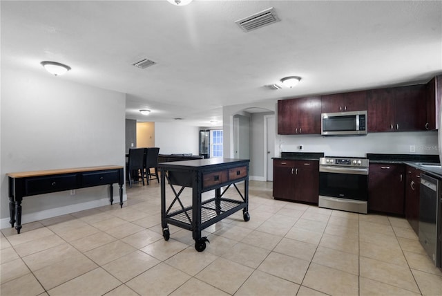 kitchen with appliances with stainless steel finishes, dark brown cabinets, and light tile patterned flooring