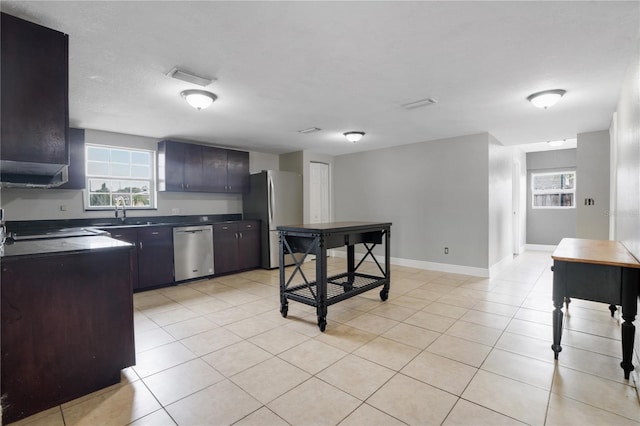 kitchen with light tile patterned flooring, sink, dark brown cabinetry, and stainless steel appliances