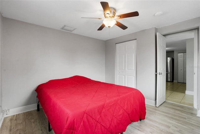 bedroom with stainless steel refrigerator, ceiling fan, a closet, and light wood-type flooring