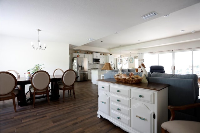 kitchen with backsplash, appliances with stainless steel finishes, a notable chandelier, white cabinetry, and dark hardwood / wood-style floors