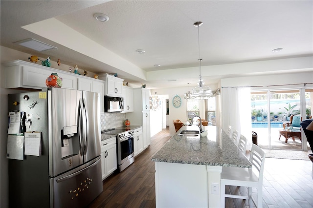 kitchen with dark wood-type flooring, stainless steel appliances, a center island with sink, and sink