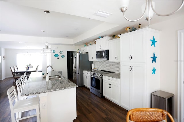 kitchen featuring white cabinets, stainless steel appliances, dark hardwood / wood-style flooring, sink, and an island with sink