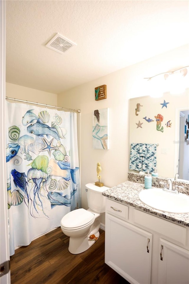 bathroom with a textured ceiling, vanity, hardwood / wood-style floors, toilet, and a shower with curtain