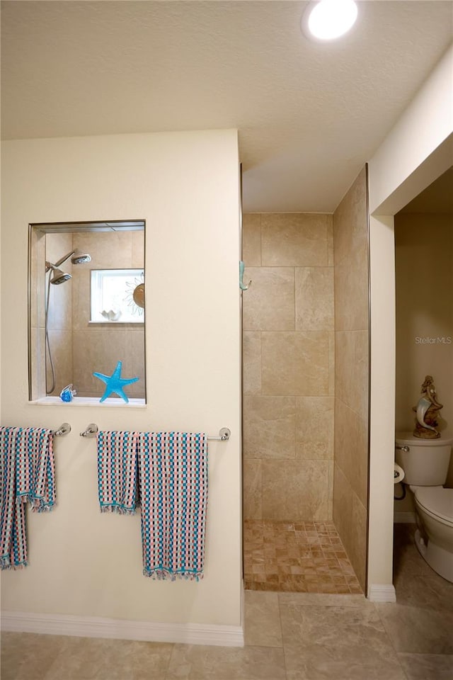 bathroom featuring toilet and a tile shower