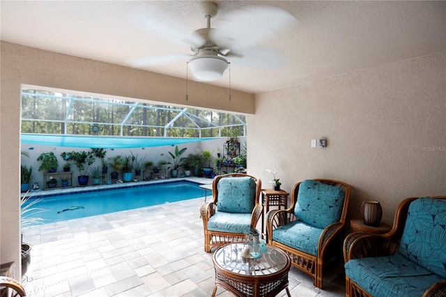 view of swimming pool featuring glass enclosure, a patio, and ceiling fan